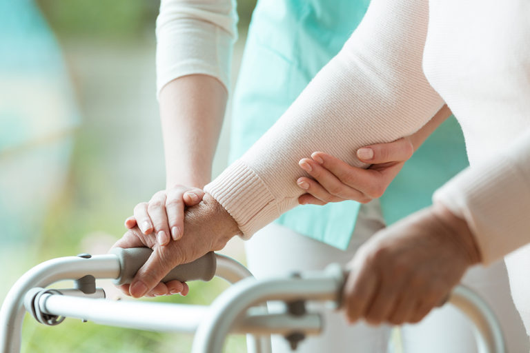 Close-up photo of patient's hands placed on metal walker