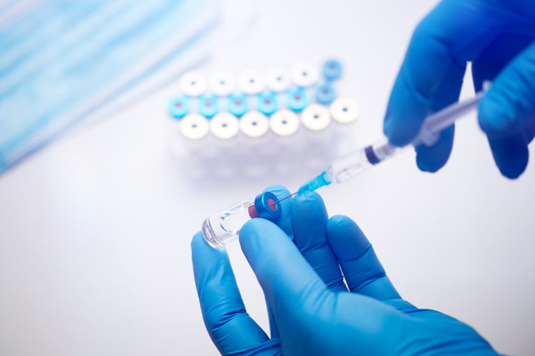 Close up on vaccine and medical syringe