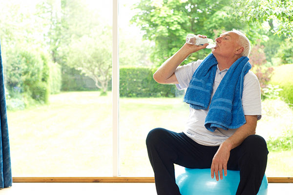 Older man drinking water during exercise