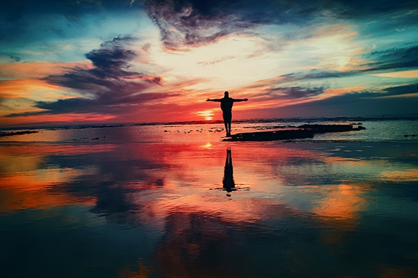 Person full of life standing on beach at sunset